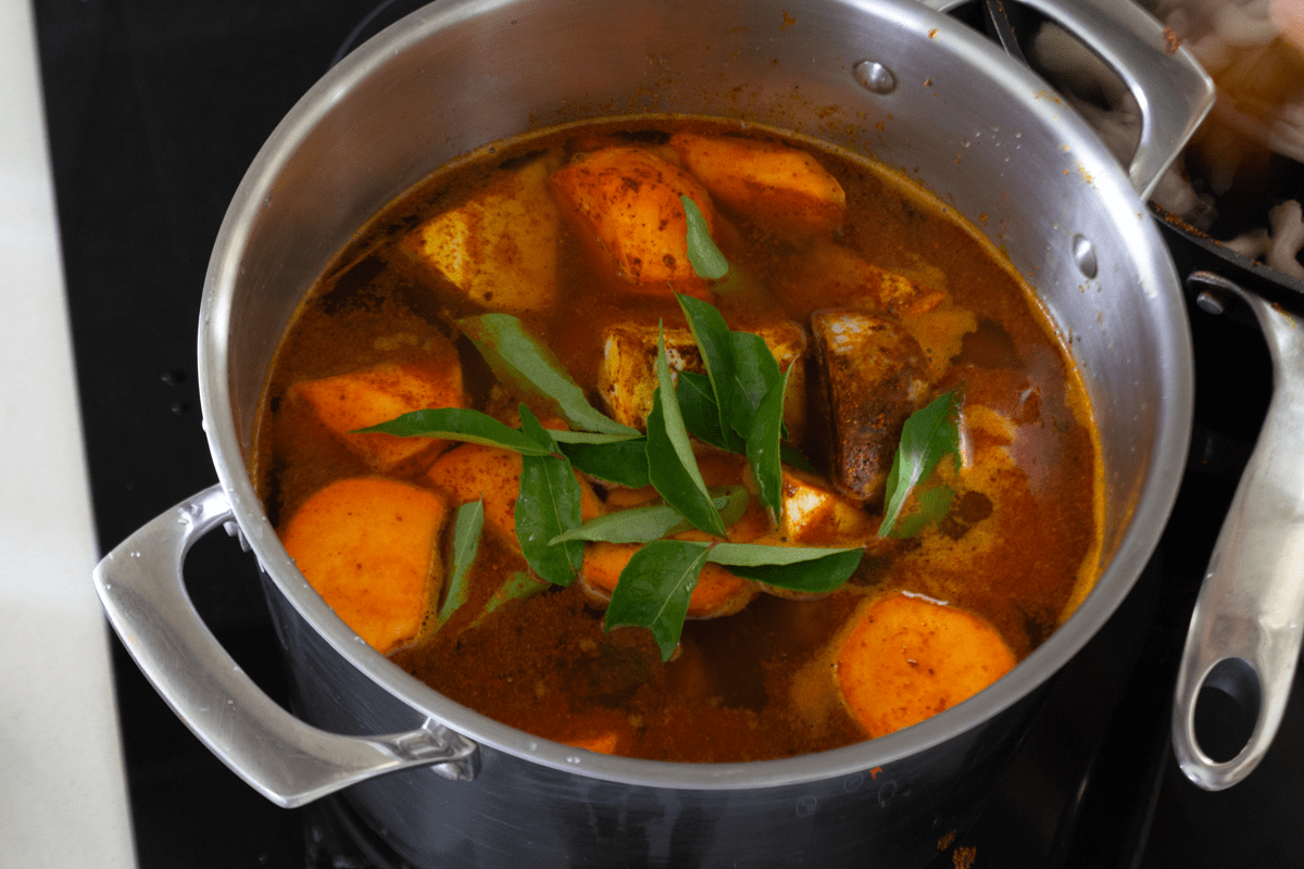 Vegetables and curry leaves in a pot of water.