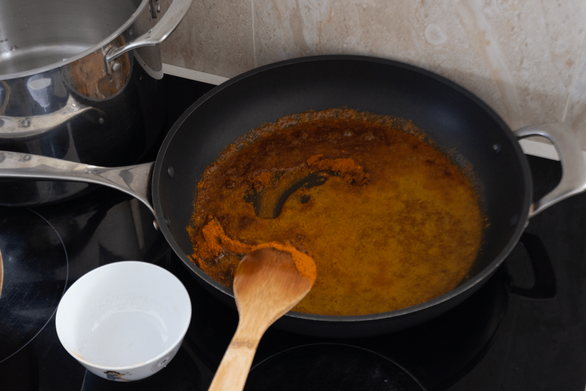 Curry powder in a pan with a wooden spoon.