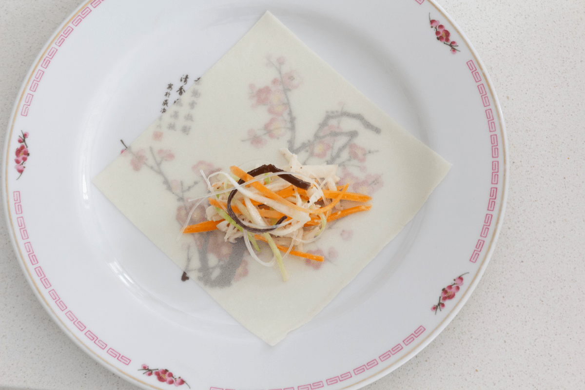 Spring roll filling on a wrapper on a plate.